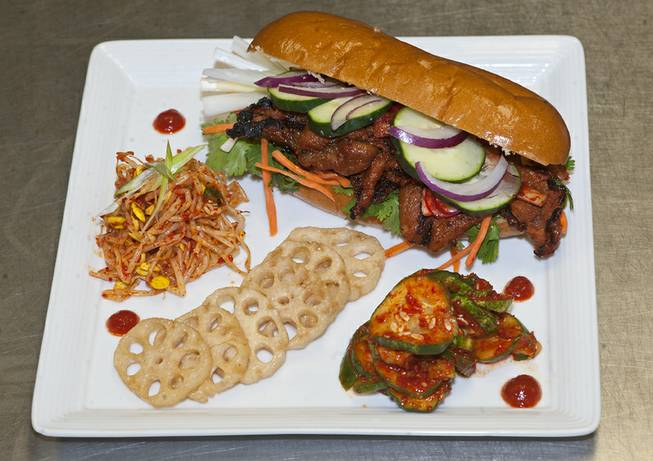 A Bahn Mi made with Vietnamese French bread, filled with chargrilled pork, radish kimchi, carrots, and cucumbers, served with sun sprouts and lotus root chips created by Chef Rob inside the DiVine Cafe at Springs Preserve.
