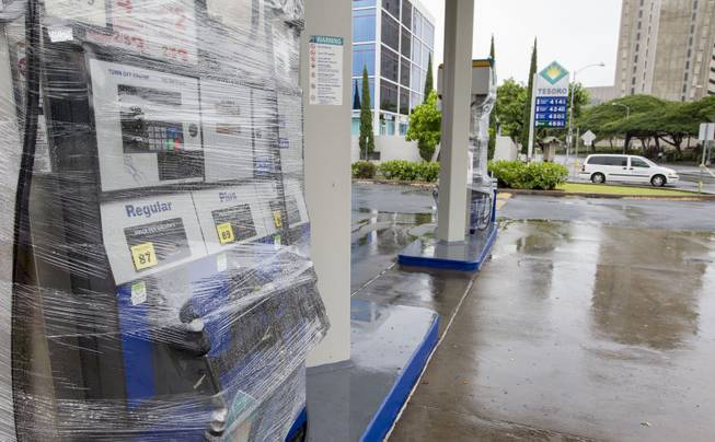 Plastic wrap covers pumps at a gas station as it and other businesses in Honolulu on the island of Oahu were closed due to Tropical Storm Iselle on Friday, Aug, 8, 2014. Iselle came ashore onto the Big Island early Friday as a weakened tropical storm, while Hurricane Julio, close behind it, is forecasted to pass north of the islands. Iselle is the first tropical storm to hit the state in 22 years. 