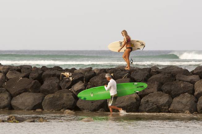 Two surfers head for the waves in Honolulu on Friday, Aug, 8, 2014. High surf is expected in some spots on Oahu due to Tropical Storm Iselle. Iselle came ashore early Friday as a weakened tropical storm, while Hurricane Julio, close behind it, strengthened and is forecasted to pass north of the islands. Iselle is the first tropical storm to hit the state in 22 years. 