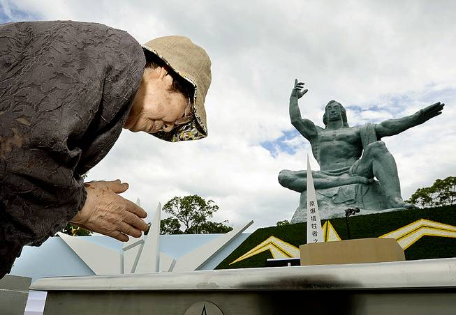 A woman offer a prayer in front of the Statue of Peace at Nagasaki Peace Park in Nagasaki, southern Japan Saturday, Aug. 9, 2014 to mark the 69th anniversary of the world's second atomic bomb attack.