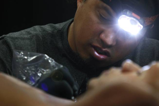 George "Keoki" Davis works an a tattoo at the 3rd annual Art-N-Ink Tattoo Festival Saturday, Aug. 9, 2014 at the South Point.