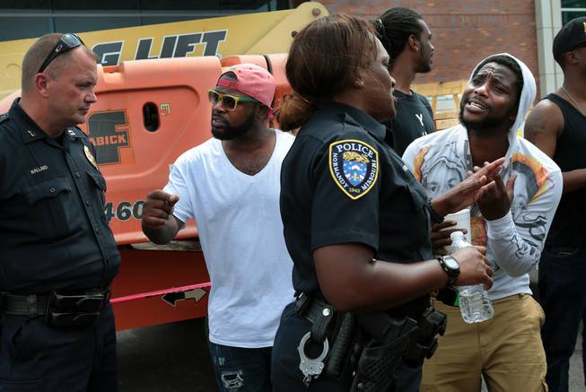 Jamahl Spence, right, pleads his case with a Normandy police officer in front of the Ferguson, Mo. police station on Sunday, Aug. 10, 2014, one day after a Ferguson officer shot and killed Michael Brown.