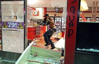 A man jumps through a broken window with bottles of wine in his hands as a QuikTrip store is looted Sunday, Aug. 10, 2014, in Ferguson, Mo. A few thousand people crammed a suburban St. Louis street Sunday night at a vigil for unarmed 18-year-old Michael Brown shot and killed by a police officer, while afterward several car windows were smashed and stores were looted as people carried away armloads of goods as witnessed by an an Associated Press reporter.