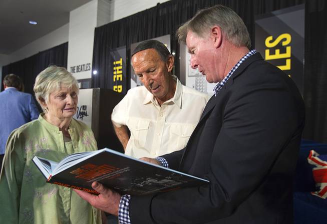 Author Chuck Gunderson shows his book about the Beatles to Bill and Dorothea Tannenbaum during a news conference in the lobby of the Las Vegas Convention Center Tuesday, Aug. 12, 2014. Bill Tannenbaum was an agent who traveled with the Beatles for part of their tour, his wife said. The event celebrated the 50th anniversary of the Beatles concert in Las Vegas on August 20, 1964. A multi-media exhibition commemorating the event will be on display in the lobby of the LVCC through Oct. 27.