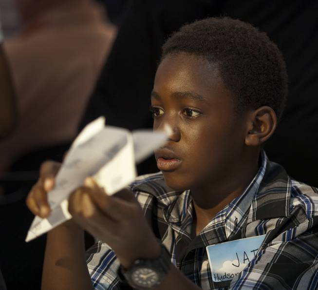 Jai Leveston, 12, with team Hudson News joins others in folding their airplanes before the Paper Plane Palooza competition begins at McCarran International Airport on Tuesday, August 12, 2014.  He would go on to win the long distance throw as a member of the Boys & Girls Clubs of Southern Nevada.