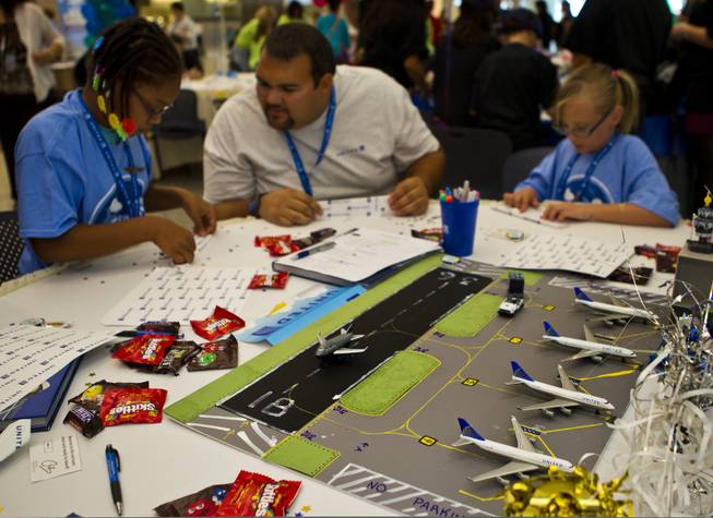 The United Airlines team members fold their airplanes before the Paper Plane Palooza competition begins at McCarran International Airport on Tuesday, August 12, 2014.