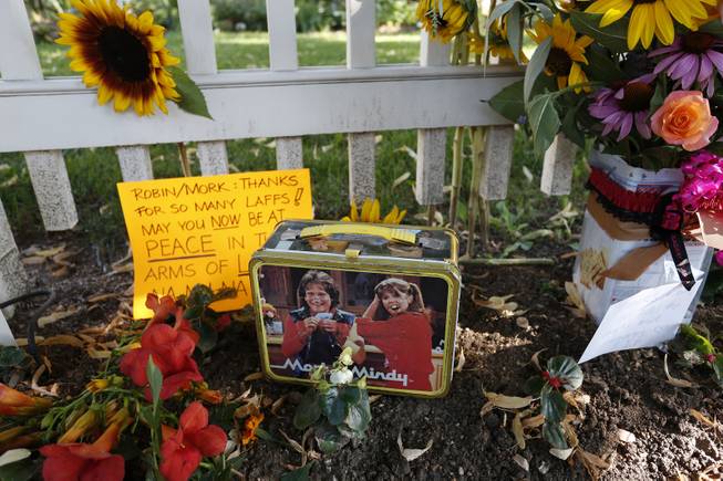 Flowers, notes, and a Mork & Mindy commemorative lunchbox are among the things left at a makeshift memorial in Boulder, Colo., Tuesday Aug. 12, 2014, outside the home where the 80s TV series Mork & Mindy, starring the late Robin Williams, was set. Williams, the Academy Award winner and comic supernova whose explosions of pop culture riffs and impressions dazzled audiences for decades and made him a gleamy-eyed laureate for the Information Age, died Monday, Aug. 11, in an apparent suicide. He was 63. 