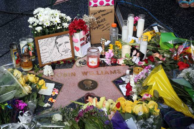 Flowers, photographs and candles surround the star of actor-comedian Robin Williams along the Hollywood Walk of Fame in Los Angeles on Tuesday, Aug. 12, 2014. Williams, 63, died at his San Francisco Bay Area home Monday in an apparent suicide. 