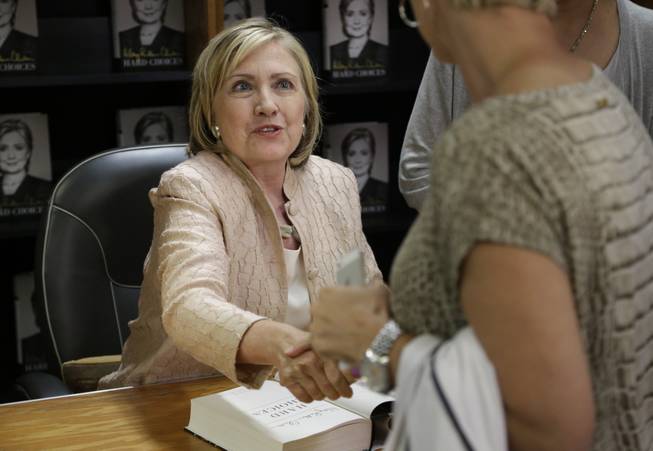 Former Secretary of State Hillary Rodham Clinton shakes hands with a customer at Bunch of Grapes Bookstore, in Vineyard Haven, Mass., on the island of Martha's Vineyard, Wednesday, Aug. 13, 2014, during a book signing event for her memoir "Hard Choices."  Clinton says she's looking forward to hugging out her differences with President Barack Obama. Obama's former secretary of state told reporters Wednesday that she's proud to have served with him despite some differences of opinion.