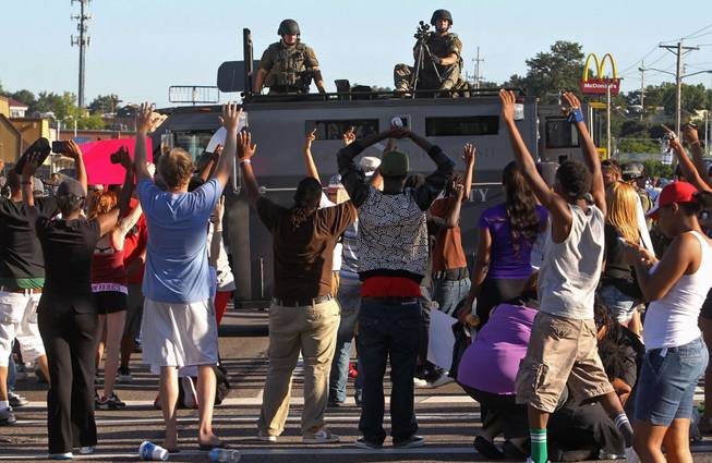 Protesters raise their hands in front of police atop an armored vehicle in Ferguson, Mo. on Wednesday, Aug. 13, 2014. On Saturday, Aug. 9, 2014, a white police officer fatally shot Michael Brown, an unarmed black teenager, in the St. Louis suburb.