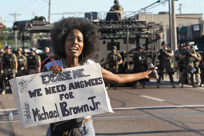 A protester shouts as she moves away from a line of riot police in Ferguson, Mo. on Wednesday, Aug. 13, 2014. On Saturday, Aug. 9, 2014, a white police officer fatally shot Michael Brown, an unarmed black teenager, in the St. Louis suburb.