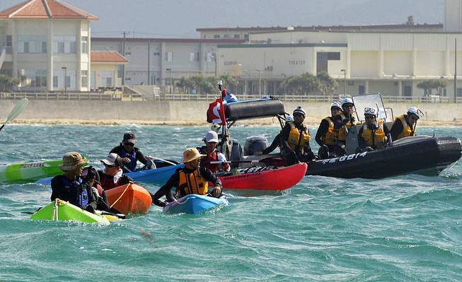 Anti-U.S. base protesters in canoe are blocked by a Japan Coast Guard speed boat in Nago, Okinawa, southern Japan, Thursday, Aug. 14, 2014. Japanese officials said buoys are being floated off the southernmost island of Okinawa in one of the first steps in the relocation of an American military base.
