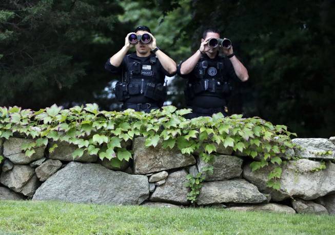Two law enforcement officials use binoculars near the entrance to State Road Restaurant, Saturday, Aug. 16, 2014, in West Tisbury, Mass., moments before the arrival of President Barack Obama and first lady Michelle Obama for dinner with friends. President Obama is staying on Martha's Vineyard for what is expected to be a two-week summer vacation. (AP Photo/)
