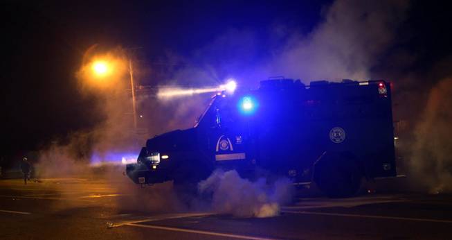 A tactical trucks moves down the street through tear gas in Ferguson, Mo., Sunday, Aug. 17, 2014. Protests over the killing of 18-year-old Michael Brown by a white police officer have entered their second week. 