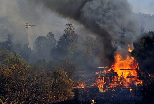 A structure burns along Highway 41 in Oakhurst, Calif., Monday, Aug. 18, 2014. One of several wildfires burning across California prompted the evacuation of hundreds of people in a central California foothill community near Yosemite National Park, authorities said.