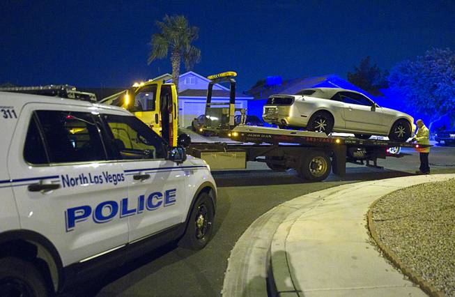 A tow truck driver removes the victim's car from a shooting scene after a fatal shooting in North Las Vegas Sunday, Aug. 24, 2014. 