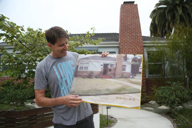 Rick Blankenship holds a photo of his previous grass lawn at his home in Long Beach, Calif. As Californians face a historic drought, more people are tearing out thirsty grass lawns to cut down on water use.
