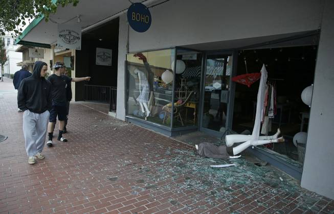 People walk past a tumbled mannequin and broken storefront window on First Street following an earthquake Sunday, Aug. 24, 2014, in Napa, Calif. A large earthquake rolled through California's northern Bay Area early Sunday, damaging some buildings, igniting fires, knocking out power to tens of thousands and sending residents running out of their homes in the darkness.