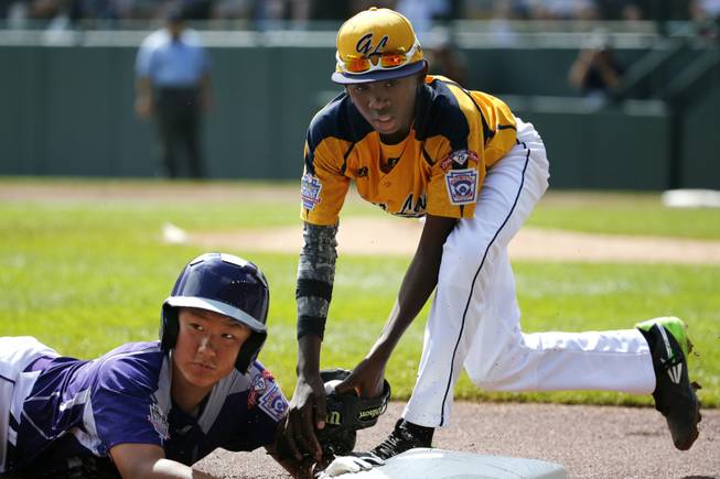 South Korea's Jae Yeong Hwang, left, is tagged out by Chicago's Cameron Bufford while attempting to steal third in the first inning of the Little League World Series championship baseball game in South Williamsport, Pa., Sunday, Aug. 24, 2014.