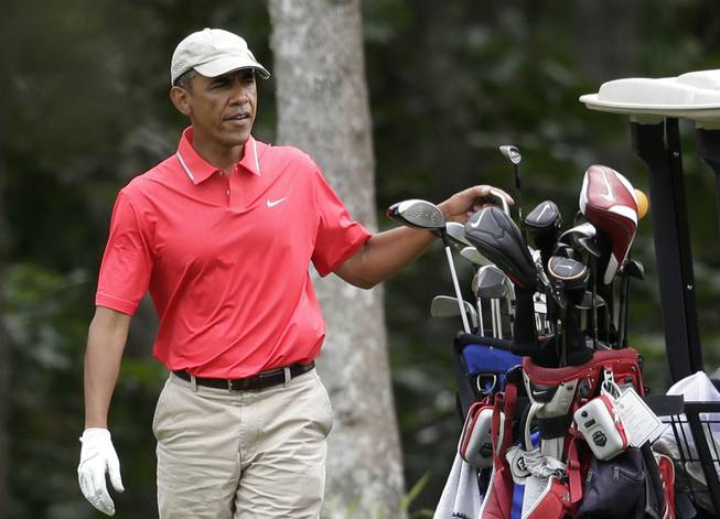 President Barack Obama selects a club while golfing at Farm Neck Golf Club, in Oak Bluffs, Mass., on the island of Martha's Vineyard, Saturday, Aug. 23, 2014. Obama is vacationing on the island.