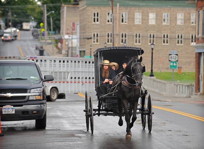 In this Aug. 15, 2014, file photo, an Amish family rides along Route 812 in Heuvelton, N.Y., near the command center of the investigation into the abduction and return of two young Amish girls at the Heuvelton Volunteer Fire Department. Members of an extended Amish family plan to hold a “garage raising” for the couple who returned the two kidnapped Amish girls to their home, according to the the Watertown Daily Times.