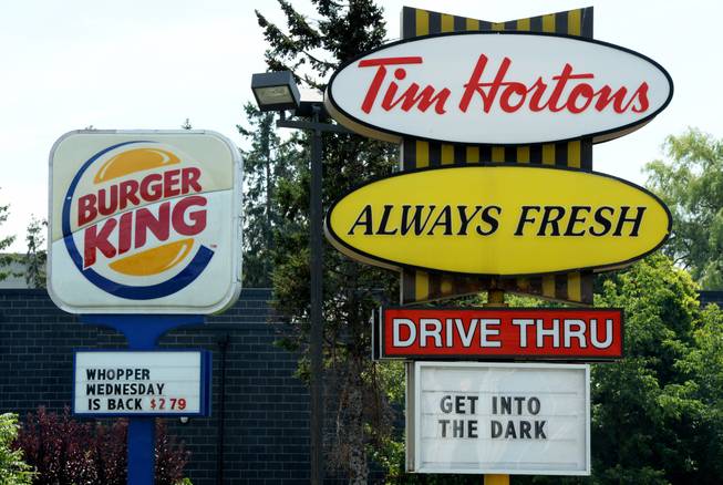 A Burger King sign and a Tim Hortons sign are displayed on St. Laurent Boulevard in Ottawa, Canada, on Monday, Aug. 25, 2014.