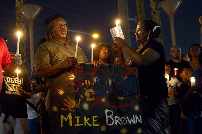 People hold candles during a vigil for Michael Brown at Martin Luther King Boulevard and Carey Avenue Thursday, Aug. 28, 2014. Brown, 18, was shot and killed by a police officer Aug. 9, 2014, in Ferguson, Mo.