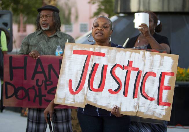 Sheila Taylor, center, holds a sign during a vigil for Michael Brown at Martin Luther King Boulevard and Carey Avenue Thursday, August 28, 2014. Brown, 18, was shot and killed by a police officer Aug. 9, 2014 in Ferguson, Mo. 