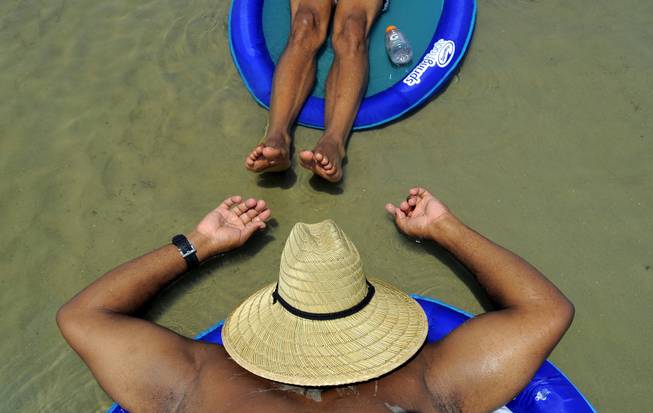 AP10ThingsToSee- Ron Mcgee, bottom, and Shawn Williams sunbathe on a float in a shallow tidal pool, Saturday, Aug. 23, 2014, on the South Beach of Tybee Island, Ga. National Weather Service has issued a heat advisory in south Georgia. (AP Photo/Stephen B. Morton)