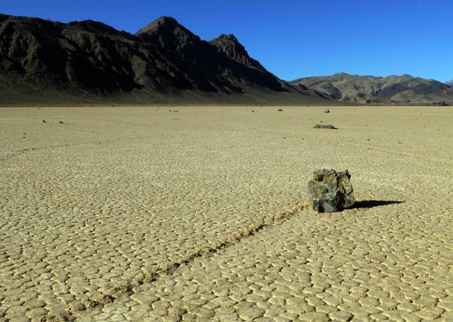 This undated photo provided by the National Park Service shows rocks that have moved across a dry lake bed in Death Valley National Park in California's Mojave Desert. For years scientists have theorized about how the large rocks — some weighing hundreds of pounds — zigzag across Racetrack Playa leaving long trails etched in the earth.