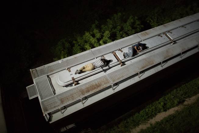 In this Aug. 26, 2014 photo, Central American migrants sleep atop a moving freight train as it heads north from Arriaga toward Chahuites, Mexico. A Mexican crackdown seems to be keeping women and children off the deadly train, known as "The Beast," that has traditionally helped thousands of migrants head north. The once-open route to the United States has become so difficult that trains now carry a small fraction of the migrants they used to, and almost exclusively adult men. 