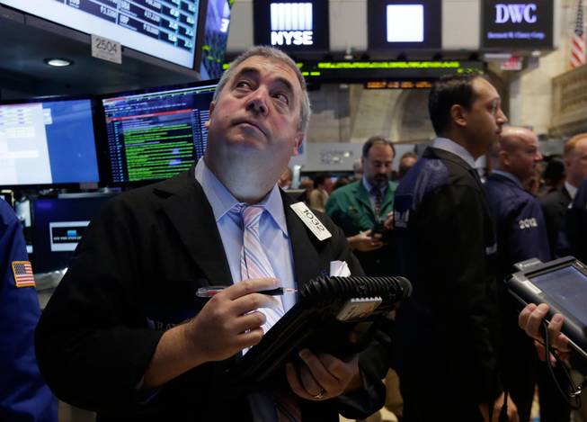 FILE - In this Thursday, Aug. 21, 2014, file photo, trader Edward McCarthy, left, works on the floor of the New York Stock Exchange. As stocks continue to rise, investors are wondering if it’s time to sell. 