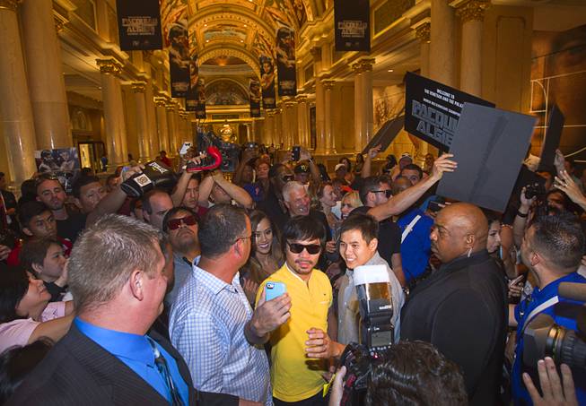 Boxer Manny Pacquiao, center, of the Philippines takes a selfie with a fan as he arrives at the Venetian Saturday, Aug. 30, 2014. Pacquiao and his opponent Chris Algieri of Huntington, N.Y. are on day six of an international tour promoting their WBO welterweight title fight in Macau, China on November 22, 2014.