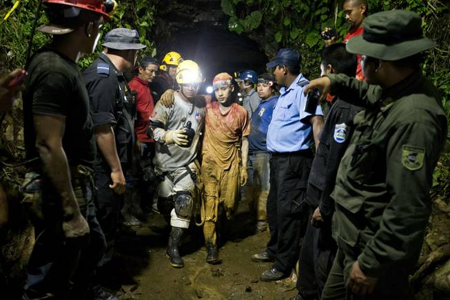 Miner Leber Vivas Gonzales, 16, center right, walks with his his arm over the shoulders of a rescue worker after he was rescued from the El Comal gold and silver mine in Bonanza, Nicaragua, late Friday, Aug. 29, 2014. Nicaraguan rescuers have saved 22 of at least 26 workers trapped in a mine collapse and were working Saturday to free the rest, officials said.