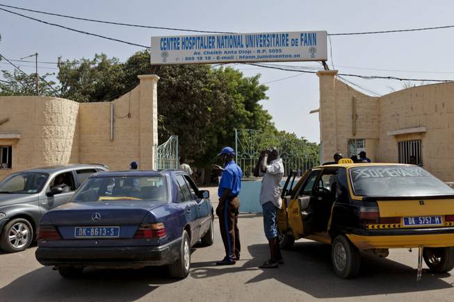 A security guard, center left, working at the University Hospital Fann, speaks to people inside a car as a man is treated for symptoms of the Ebola virus inside the Hospital in Dakar, Senegal. The effort to contain Ebola in Senegal is “a top priority emergency,” the World Health Organization said Sunday, as the government continued tracing everyone who came in contact with a Guinean student who has tested positive for the deadly disease in the capital, Dakar.