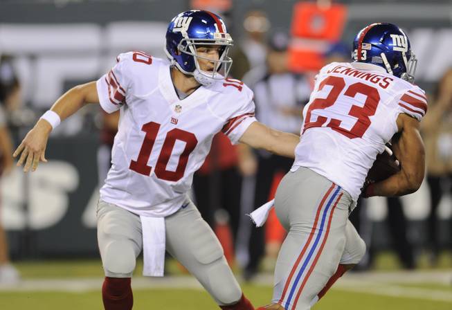 New York Giants quarterback Eli Manning (10) hands the ball off to running back Rashad Jennings (23) against the New York Jets in the first quarter of a preseason NFL football game, Friday, Aug. 22, 2014, in East Rutherford, N.J.