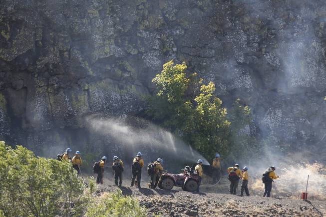 Firefighters stand along Highway 30 to assist back-burning efforts near The Dalles, Ore. on Friday morning, Aug. 8, 2014. Fire crews on both the ground and in the air set fires to burn off fuel sources in the path of the wind-driven Rowena fire, west of The Dalles. 