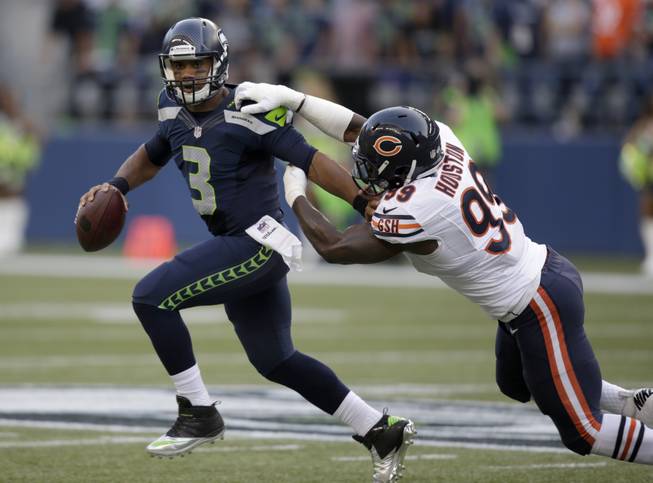Seattle Seahawks quarterback Russell Wilson (3) tries to escape the grasp of Chicago Bears defensive end Lamarr Houston in the first half of a preseason NFL football game, Friday, Aug. 22, 2014, in Seattle. The Seahawks won 34-6.