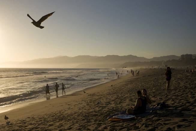 AP10ThingsToSee- People walk along the beach Friday, Aug. 29, 2014, in Santa Monica, Calif. The highest number of Californians since the recession were expected to travel over the Labor Day holiday weekend. 