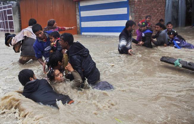 AP10ThingsToSee- Kashmiri residents wade through floodwaters in Srinagar, India, Thursday, Sept. 4, 2014. At least 100 villages across the Kashmir valley were flooded by overflowing lakes and rivers.