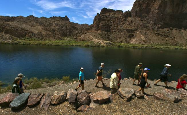 Participants hike along the Colorado River for a short hike to the River Gauger's House site during a kayak tour with Desert Adventures on Saturday, August 30, 2014. 