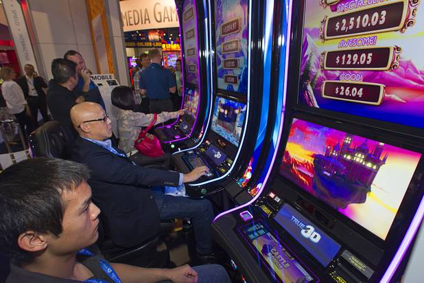 People try out Bejeweled True 3D slot machines in the GTECH booth during the final day of the Global Gaming Expo (G2E) at the Sands Expo Center Thursday, Oct. 2, 2014.