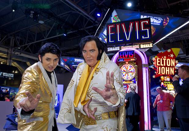 Elvis Presley impersonators Daniel Jenkins, left, and Shane Paterson pose by an Elvis-themed slot machine at the WMS Gaming booth during the Global Gaming Expo (G2E) at the Sands Expo Center Thursday, Oct. 2, 2014.