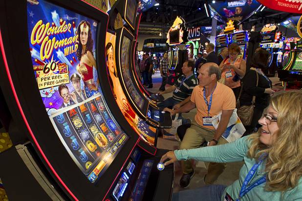Jon Leupp, center, and Dana McDermott of Na Pali Software play Wonder Woman slot machines during the Global Gaming Expo (G2E) at the Sands Expo Center Thursday, Oct. 2, 2014.