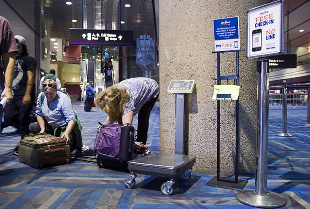 Sisters Kimberlee andrews, left, and Judy Kellaway repack their carry-on bags near the Allegiant Airlines check-in counter in McCarran International Airport Thursday, Oct. 30, 2014. 