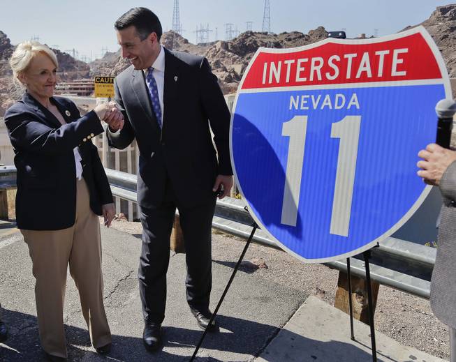 Arizona Gov. Jan Brewer shakes hands with Nevada Gov. Brian Sandoval after unveiling a sign for the future Interstate 11 on Friday, March 21, 2014, at Hoover Dam, Ariz. The two governors gathered to unveil signs that will be posted along the proposed Interstate 11. It was a symbolic effort meant to keep up momentum on the project, which is coming of age in an era of scarce highway funding.