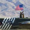 A crew member on a B-25 Mitchell bomber takes a flag down prior to take off during the 2014 Aviation Nation open house at Nellis Air Force Base Sunday, Nov. 9, 2014.