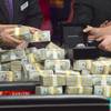 Staff place bundles of cash and the championship bracelet on the table after two finalists are determined during the 2014 World Series of Poker main event final table Tuesday, Nov. 11, 2014, at the Rio.