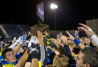 Moapa Valley players reach out to touch their winning trophy following the Division I-A state high school football championship game on Saturday, November 22, 2014. .