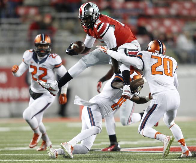 Ohio State quarterback Cardale Jones, top, tries to jump over Illinois tacklers Levaris Little, bottom, and Clayton Fejedelem during the fourth quarter of an NCAA college football game Saturday, Nov. 1, 2014, in Columbus, Ohio. Ohio State beat Illinois 55-14. (AP Photo/Paul Vernon)
